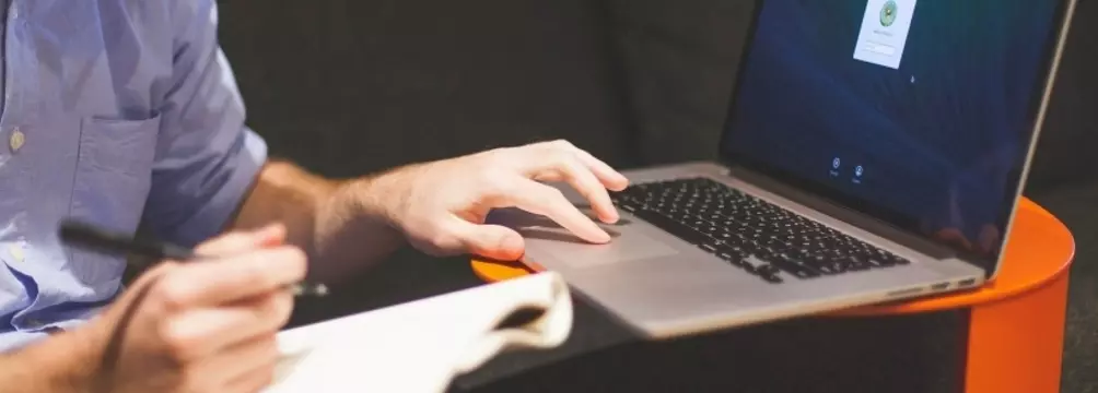 Man with Laptop and notepad taking notes image